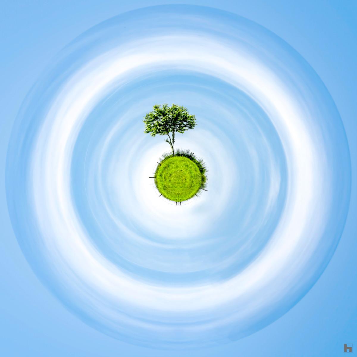 Photographie L'Arbre Solitaire de Paul Marnef – arbre isolé sur une planète verte flottant dans un ciel bleu lumineux, tirage d’art en édition limitée