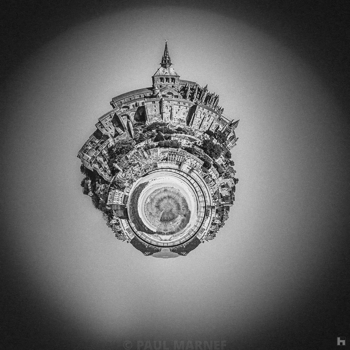 Photographie noir et blanc de Paul Marnef – Mont Saint-Michel transformé en planète surréaliste avec l’abbaye en point central, tirage d’art en édition limitée