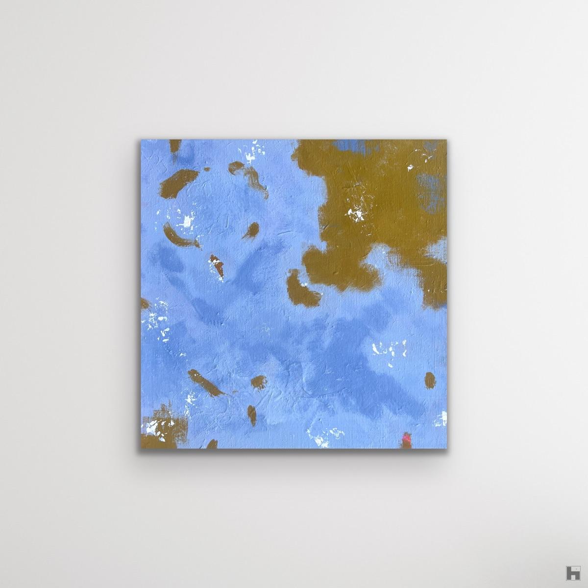 A photo of a square painting in pale blue hung on a white background