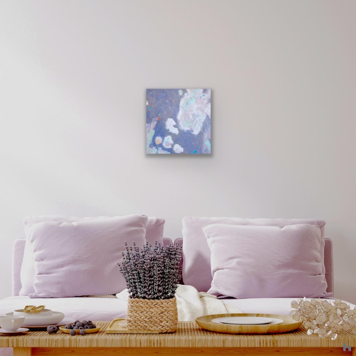 A square abstract painting in a sitting room hanging above a sofa