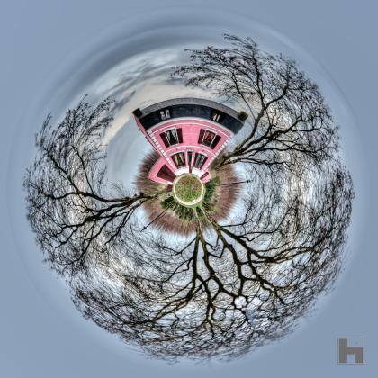 Photographie artistique "La Maison Rose" de Paul Marnef, montrant une maison rose entourée d'arbres aux branches dénudées dans un univers circulaire, issue de la série "Planètes Imaginaires", disponible en finition Chromaluxe et en édition limitée.